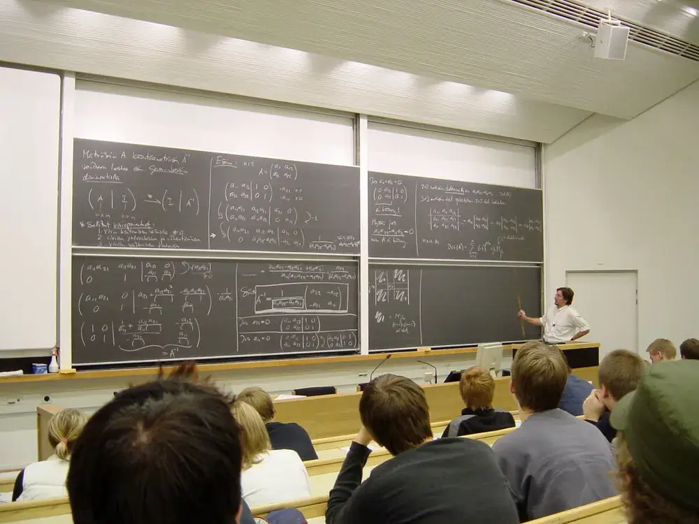 Professor teaching a mathematics lecture at a university, students taking notes